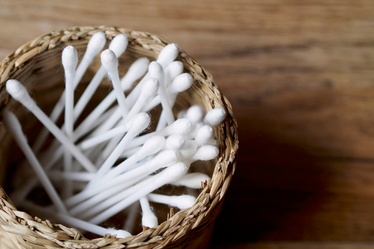Wattestäbschen in Weidenkorb auf Holztisch Hintergrund Wattestäbchen haben im Gehörgang nichts zu suchen