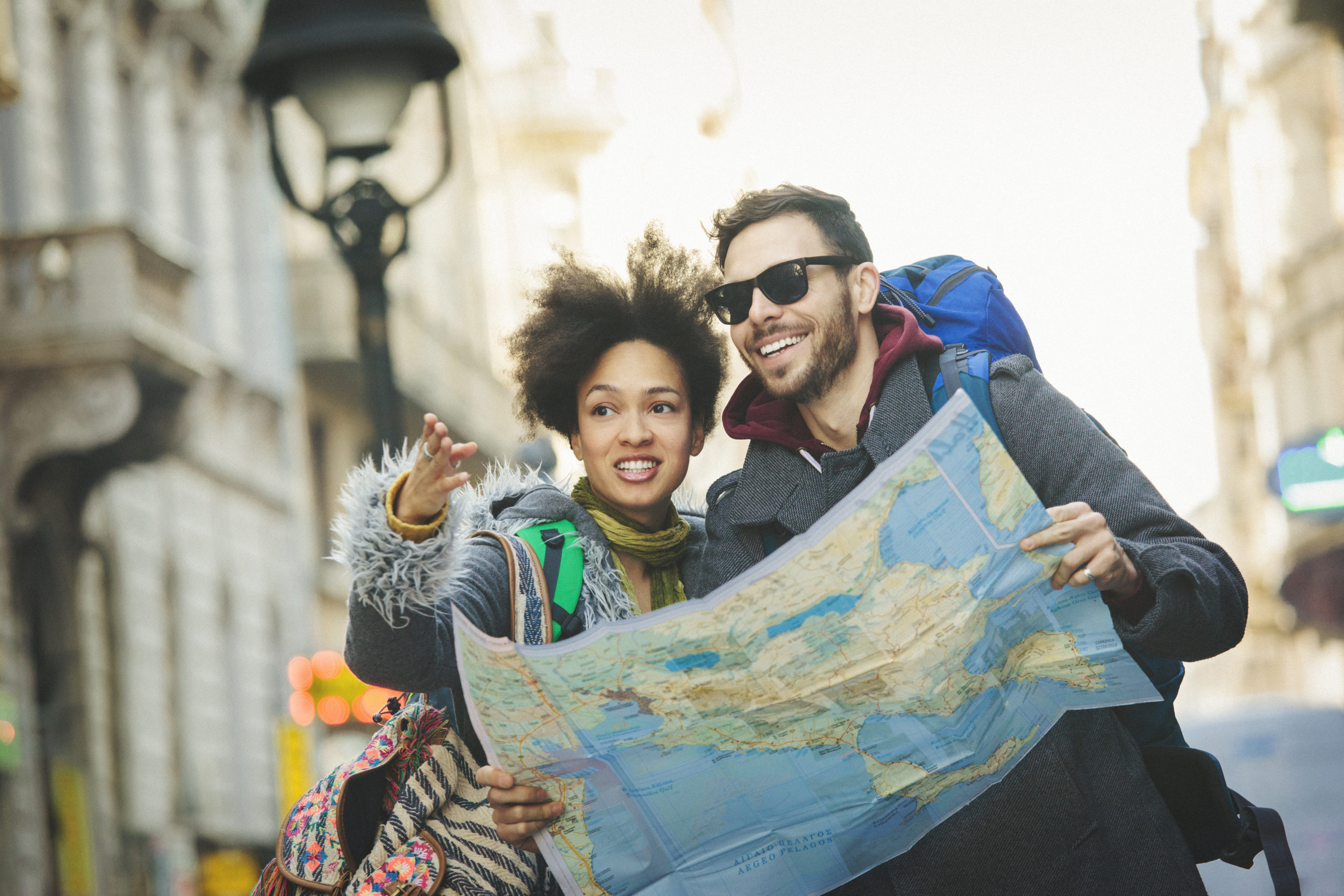 Backpacker walking using map and asking Mit den neuesten Hörgeräten kommt die Übersetzung direkt ins Ohr.