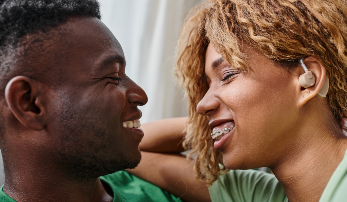 Paar laechelt sich an, Frau traegt ein Hoergeraet Paar laechelt sich an, Frau traegt ein Hoergeraet