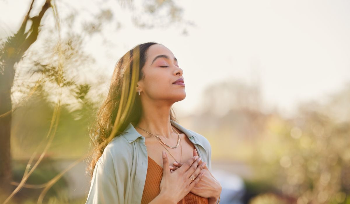 Frau steht entspannt im Freien und atmet tief durch Frau steht entspannt im Freien und atmet tief durch