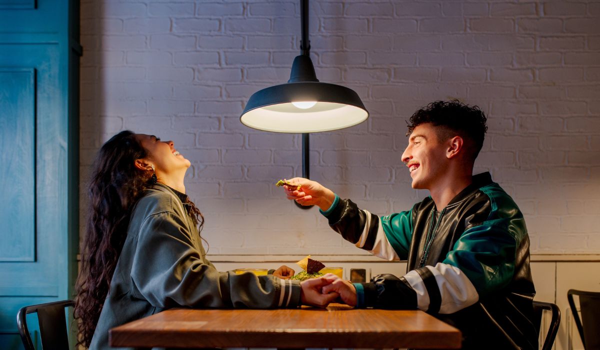 Paar-lacht-gemeinsam-bei-einem-Essen-in-gemuetlicher-Atmosphaere Paar-lacht-gemeinsam-bei-einem-Essen-in-gemuetlicher-Atmosphaere